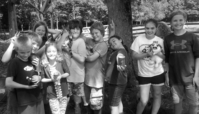 Children at farm camp holding up crafts and food they made