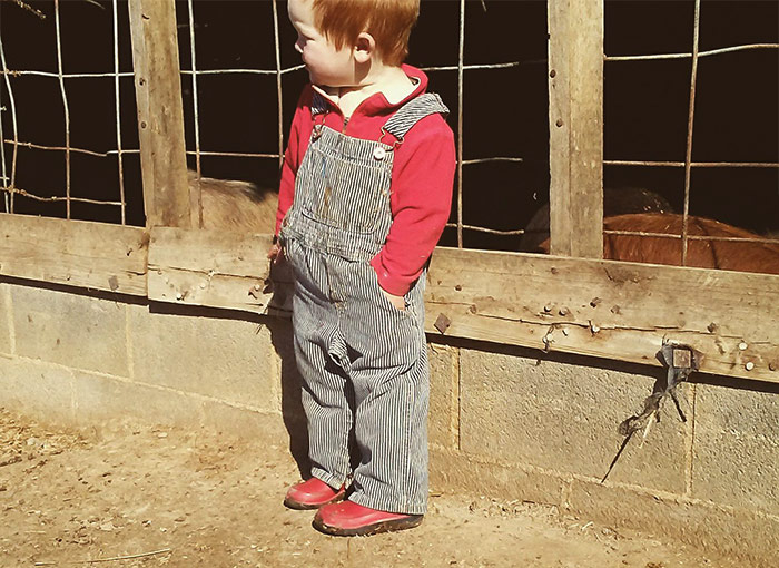 Rye Withington wearing a red shirt and shoes with blue bibbed overalls