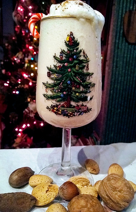 Egg nog in Christmas glass with nuts at base of glass