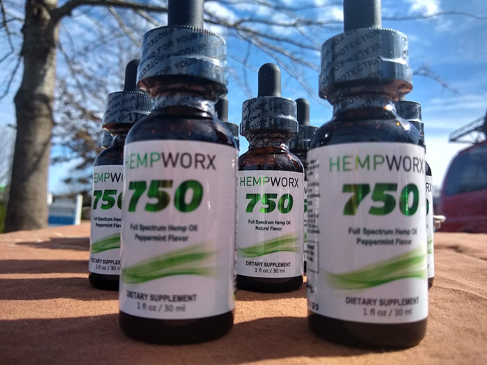 HempWorx CBD Oil Bottles on a table outside with a blue sky behind them