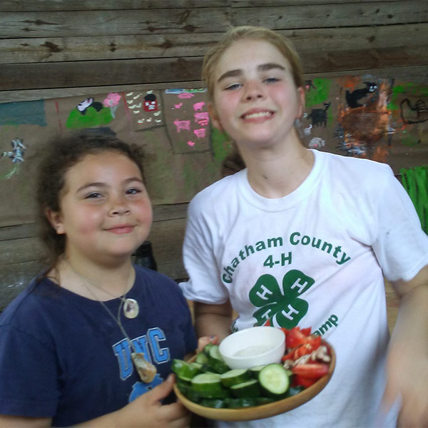 Summer camp attendees holding fresh vegetables and dip