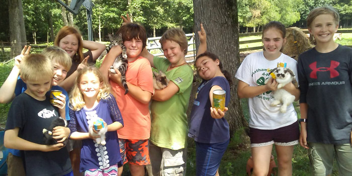 Summer camp attendees holding animals and the crafts they made at camp