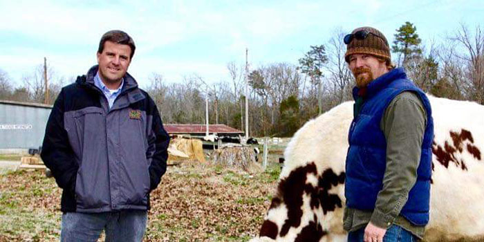 Tucker Withington and Robert Poitras standing outside with a cow