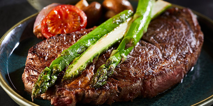 Pan fried sirloin tip steak on plate with asparagus, tomato, and mushrooms