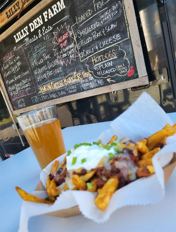 Photo of Meats and Eats loaded fries and a beer in front of chalkboard menu